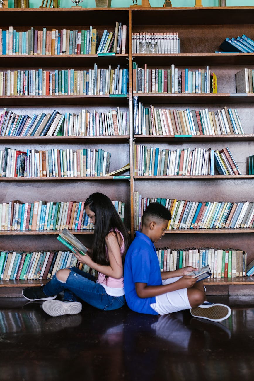 a boy and girl sitting back to back while reading books